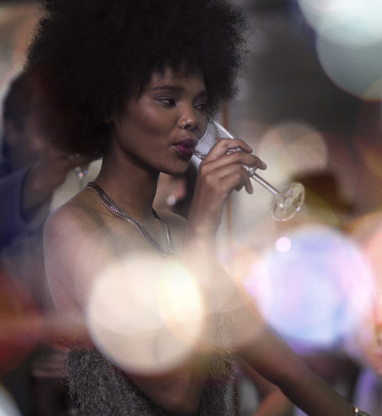 A woman sipping out of a champagne glass in a setting highlighting the atmosphere of social night life at Inglewood apartments.
